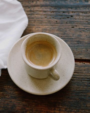 Keramiktasse mit Kaffee auf einem rustikalen Holztisch für das freie Bakgard-Coffeehouse-Konzept