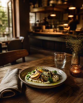 Stimmungsvoller gedeckter Restauranttisch mit handwerklich angerichtetem Gericht in einem warm beleuchteten Gastraum